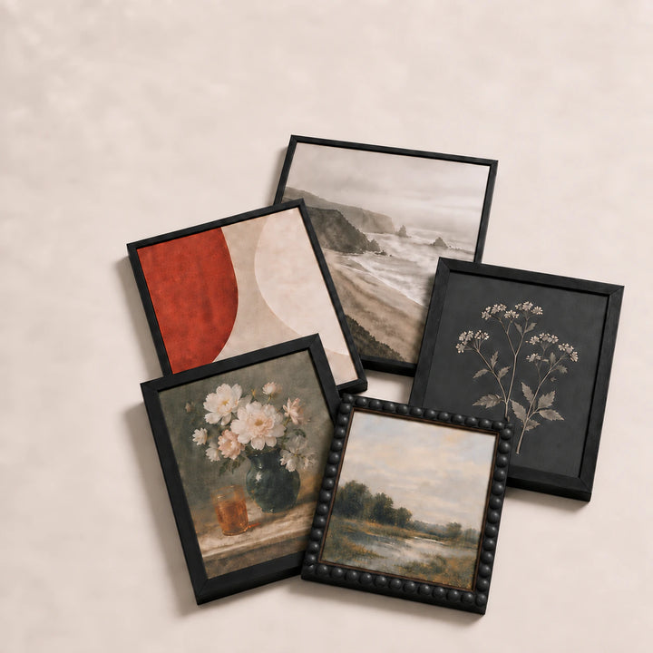 A collection of black picture frames lying flat with varied edge-to-edge artwork