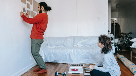 Two people planning a gallery wall layout in a living room