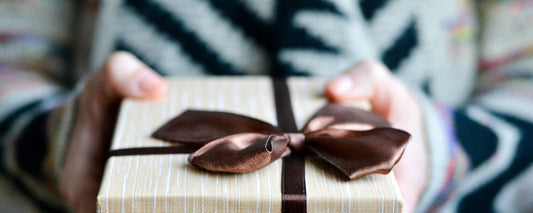 Person holding a wrapped anniversary gift with a brown ribbon