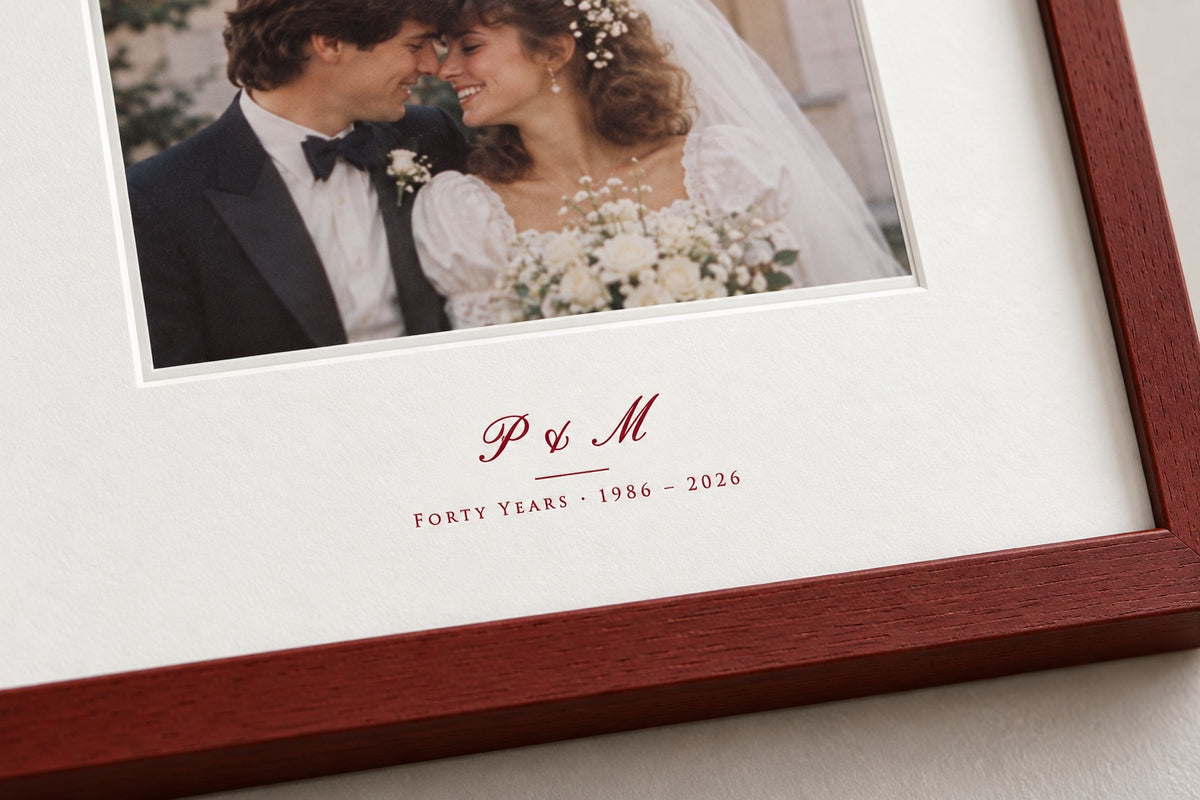 Close-up of the initials P & M and "Forty years 1986 – 2026" printed in ruby-red ink on the mat