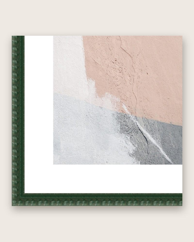 Close-up of a dark green bobbin moulding corner with a white mat board around a square print