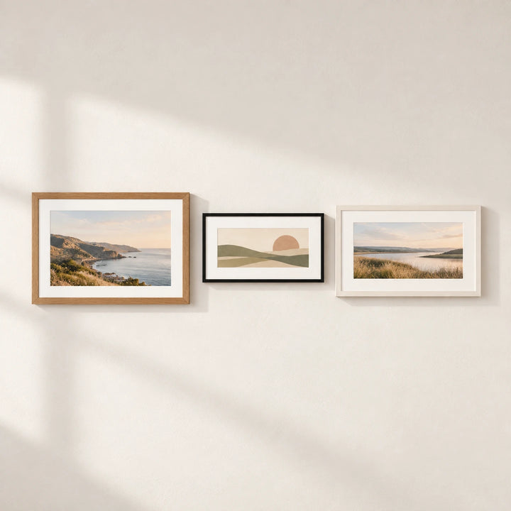 Three landscape picture frames in oak, black and white finishes displayed on a neutral wall