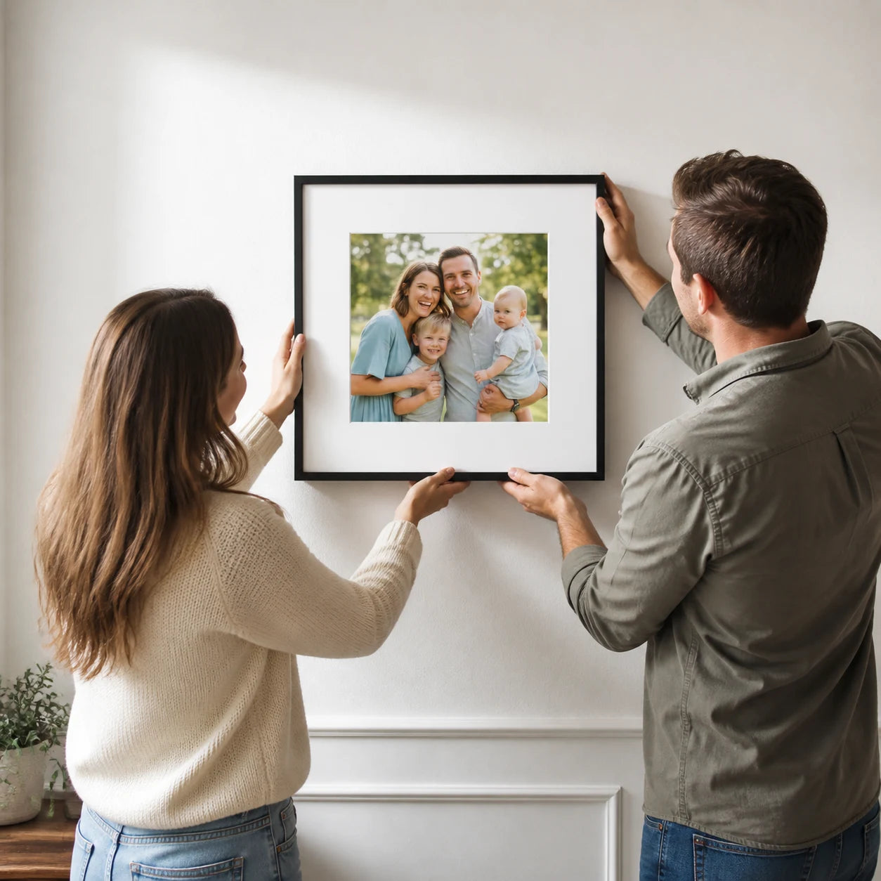 A couple hanging their finished framed family photograph